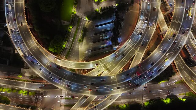 Aerial view of a complex multi-level highway interchange with heavy night traffic and illuminated roads in Shanghai, China.