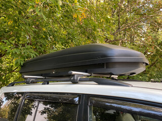 Big black box of luggage rack on the roof of car. Travel and transportation accessories.