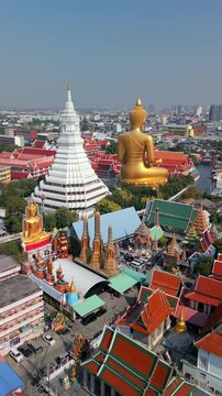 Aerial view of golden Buddha statue and ornate temples in Bangkok, Thailand. City skyline and traditional architecture create stunning cultural and spiritual landscape.