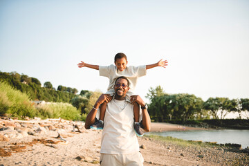 Cheerful black american father and is son against beautiful seascape