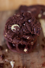 Stacked double chocolate Cookies, crumbling on a rustic wooden chopping board  