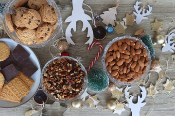 Various Christmas decorations, cookies, chocolate and nuts on wooden background. Flat lay.