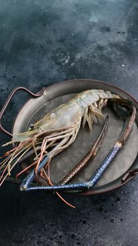 Large fresh prawns displayed on a rustic plate ready for cooking and preparation in a home kitchen setting