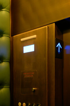 Elevator interior with green padded wall and glowing blue up arrow button. Miami, Florida, USA