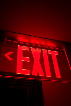 Red illuminated exit sign glowing against a dark background. Miami, Florida, USA