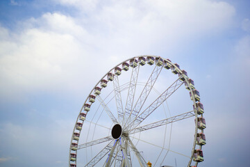 Large Ferris wheel under a cloudy blue sky with some cabins visible on the wheel. Brussels, Belgium