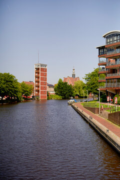 A calm canal with buildings and a church tower in a sunny urban setting. North Sea, Germany