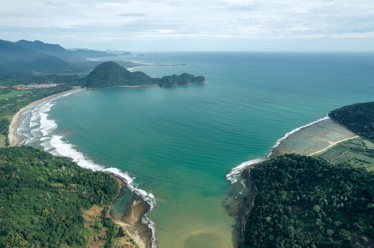 Aerial view of a scenic coastal bay with turquoise waters and lush green forested hills. Aceh Jaya Regency, Aceh, Sumatra, Indonesia