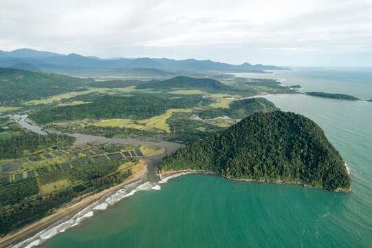 Aerial view of lush green landscape with a prominent coastal hill and vast ocean backdrop. Aceh Jaya Regency, Aceh, Sumatra, Indonesia