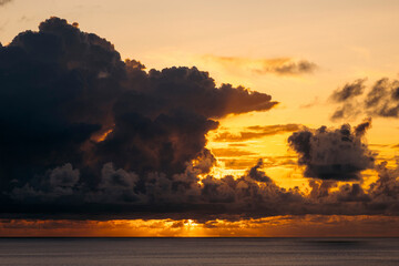 A vibrant sunset with dramatic clouds over a calm ocean horizon. Paya, on We Island in Aceh, Sumatra, Indonesia