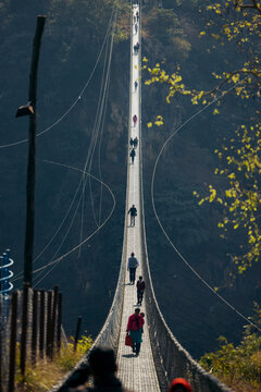 People walking on Kushma Suspension Bridge high above a mountainous landscape. Kushma, Parbat district, Gandaki province, Nepal
