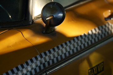 Close-up of vintage yellow taxi with retro checkered stripe and mirror, symbol of classic urban transportation and retro New York vibe  © belavinstock