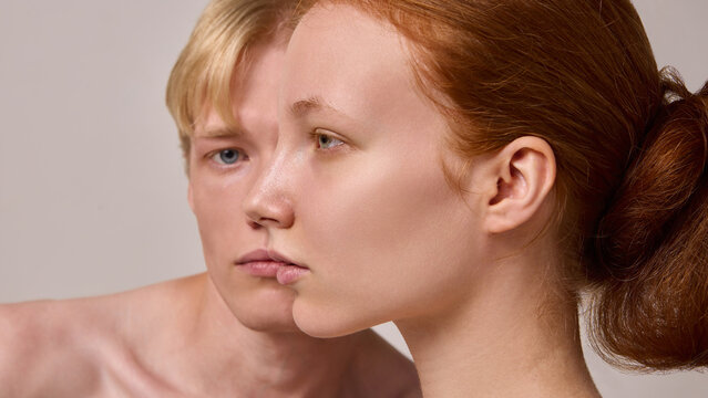 Close side profile of red-haired woman with blond man blurred behind on neutral background. Concept of gender identity, individuality, emotional portraiture, modern editorial photography.