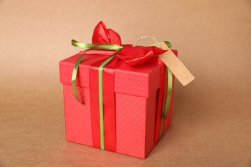 Gift box with blank tag on light brown background