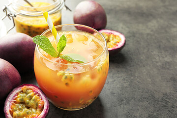 Tasty passion fruit drink with mint and fresh fruits on grey table, closeup. Space for text