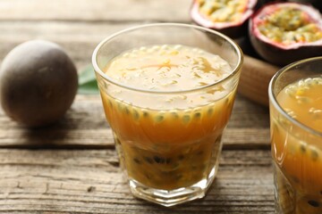 Tasty passion fruit drink and fresh fruits on wooden table, closeup