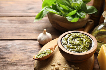 Fresh pesto sauce and ingredients on wooden table, closeup. Space for text