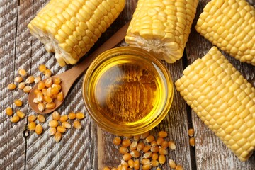 Corn oil, kernels and cobs on wooden table, flat lay