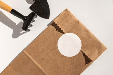 Gardening tool and brown paper bag with blank circle label on white background
