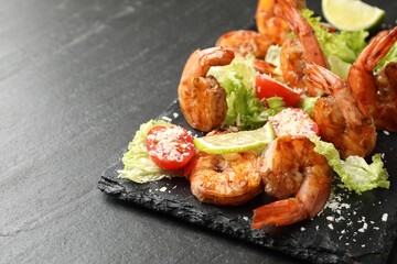 Tasty grilled shrimps with salad on black table, closeup with space for text. Delicious seafood dish