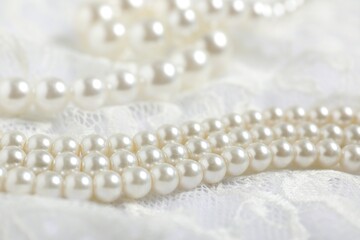Beautiful lace fabric and pearls on white background, closeup