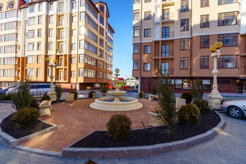 A small fountain is in the middle of a courtyard in front of a large building