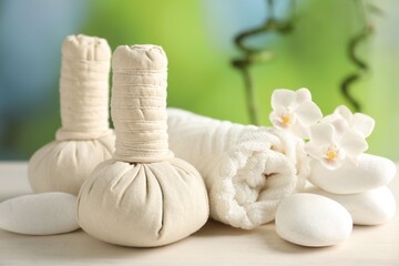 Beautiful spa composition with herbal bags on white wooden table against blurred background, closeup