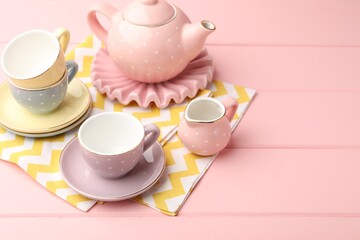 Beautiful ceramic tea set for children on pink wooden table. Space for text