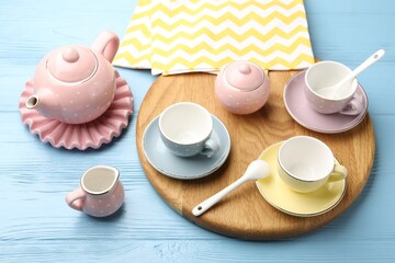 Beautiful ceramic tea set for children and napkin on light blue wooden table