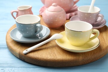 Beautiful ceramic tea set for children on light blue wooden table, closeup