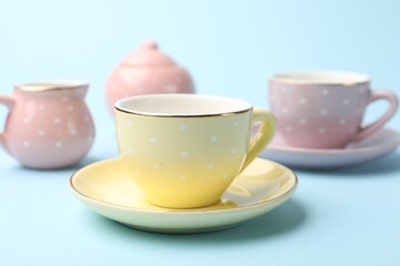 Beautiful ceramic tea set for children on light blue background, closeup