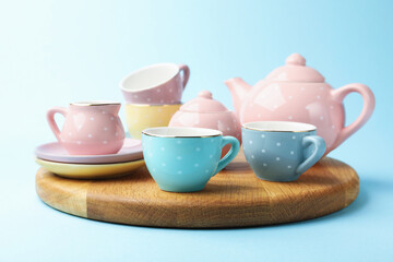 Beautiful ceramic tea set for children on light blue background, closeup