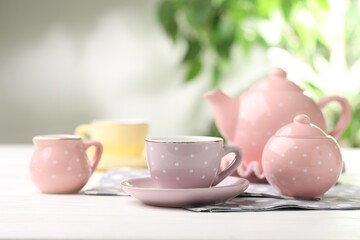 Beautiful ceramic tea set for children on white wooden table against blurred background, closeup