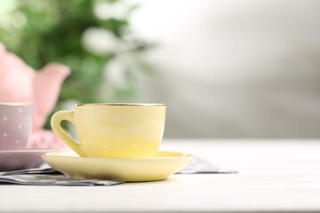 Ceramic tea set for children. Beautiful cups on white wooden table against blurred background, closeup with space for text