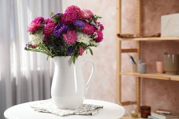 Beautiful flowers in vase on white table indoors. Space for text