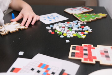 A girl makes a Christmas toy with her own hands from ceramic mosaic. Ceramic mosaic, DIY Christmas tree toy. Eco-friendly toy, educational activity for children.