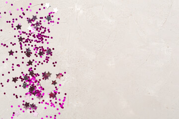 Party pink confetti on concrete background, top view
