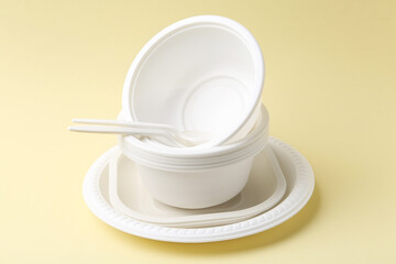 Set of disposable plastic tableware on pale yellow background