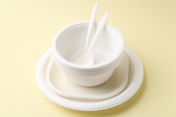 Set of disposable plastic tableware on pale yellow background