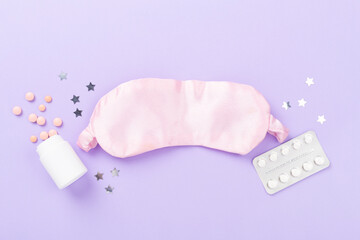 Sleeping mask with pills on color background, top view