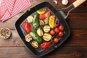 Pan with grilled vegetables and spices on wooden table, top view
