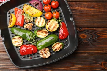 Pan with grilled vegetables and spices on wooden table, top view. Space for text