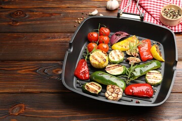 Pan with grilled vegetables and spices on wooden table, closeup. Space for text