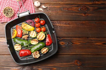 Pan with grilled vegetables and spices on wooden table, flat lay. Space for text
