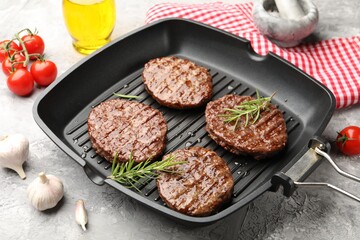 Pan with grilled patties, tomatoes and spices on grey table, closeup
