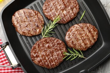 Pan with grilled patties and rosemary on table, top view