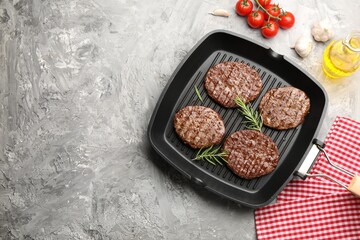 Pan with grilled patties, tomatoes and spices on grey table, flat lay. Space for text