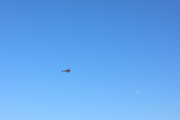 Modern helicopter flying in clear blue sky on sunny day