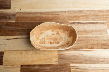 A simple, oval-shaped wooden bowl on a wooden surface
