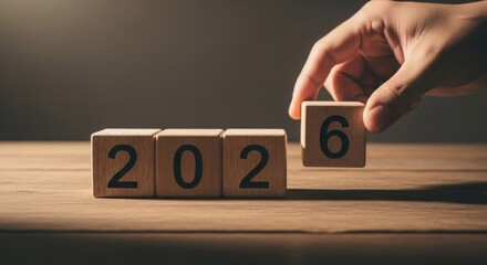 Hand adding block to year "202" to make "2026" on wood